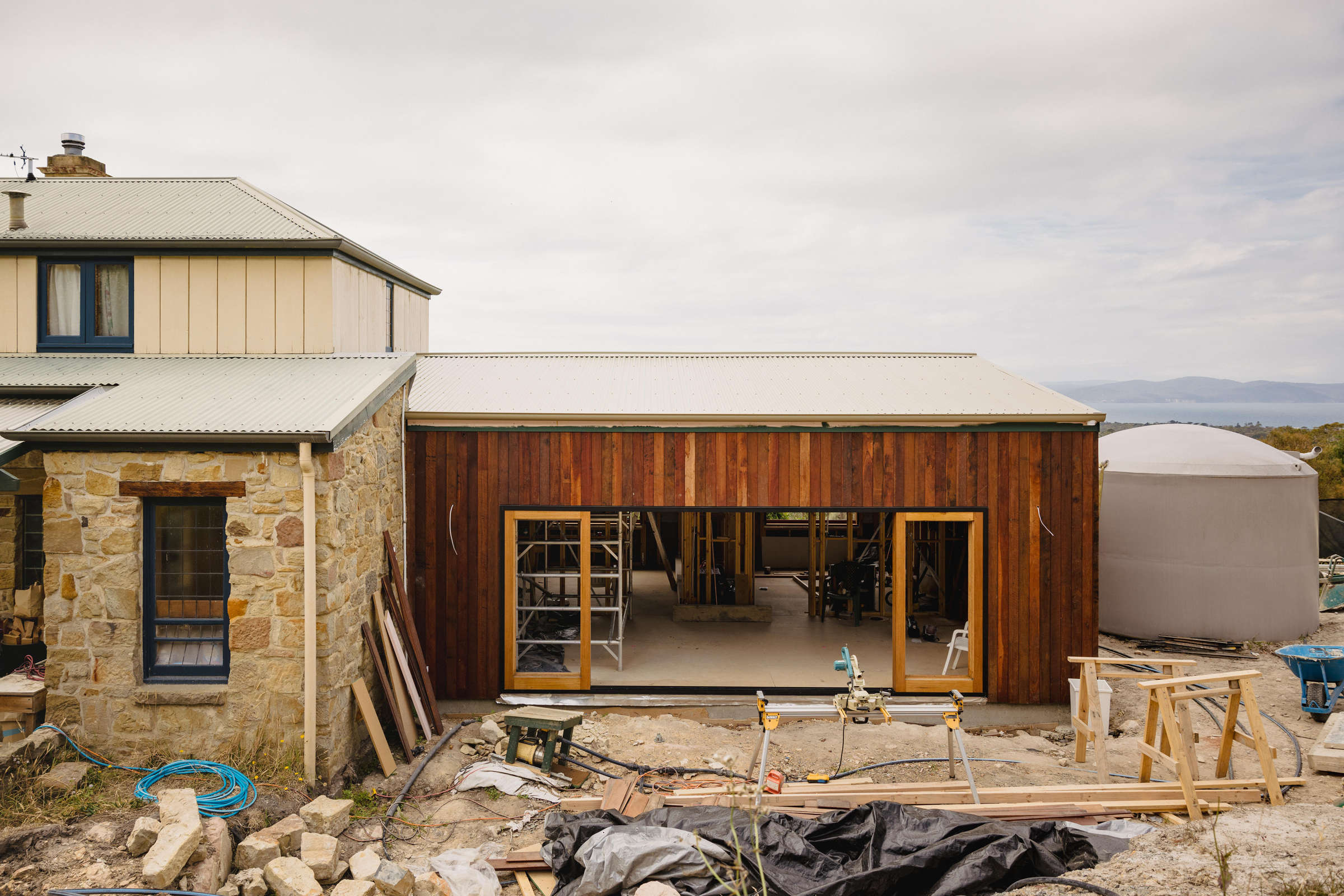 Home renovation featuring natural stone internally, stone walls, specialised timber framing and bifold doors. The renovation was completed to accommodate a growing family and take advantage of the spectacular view. Photo: Jordan Davis.