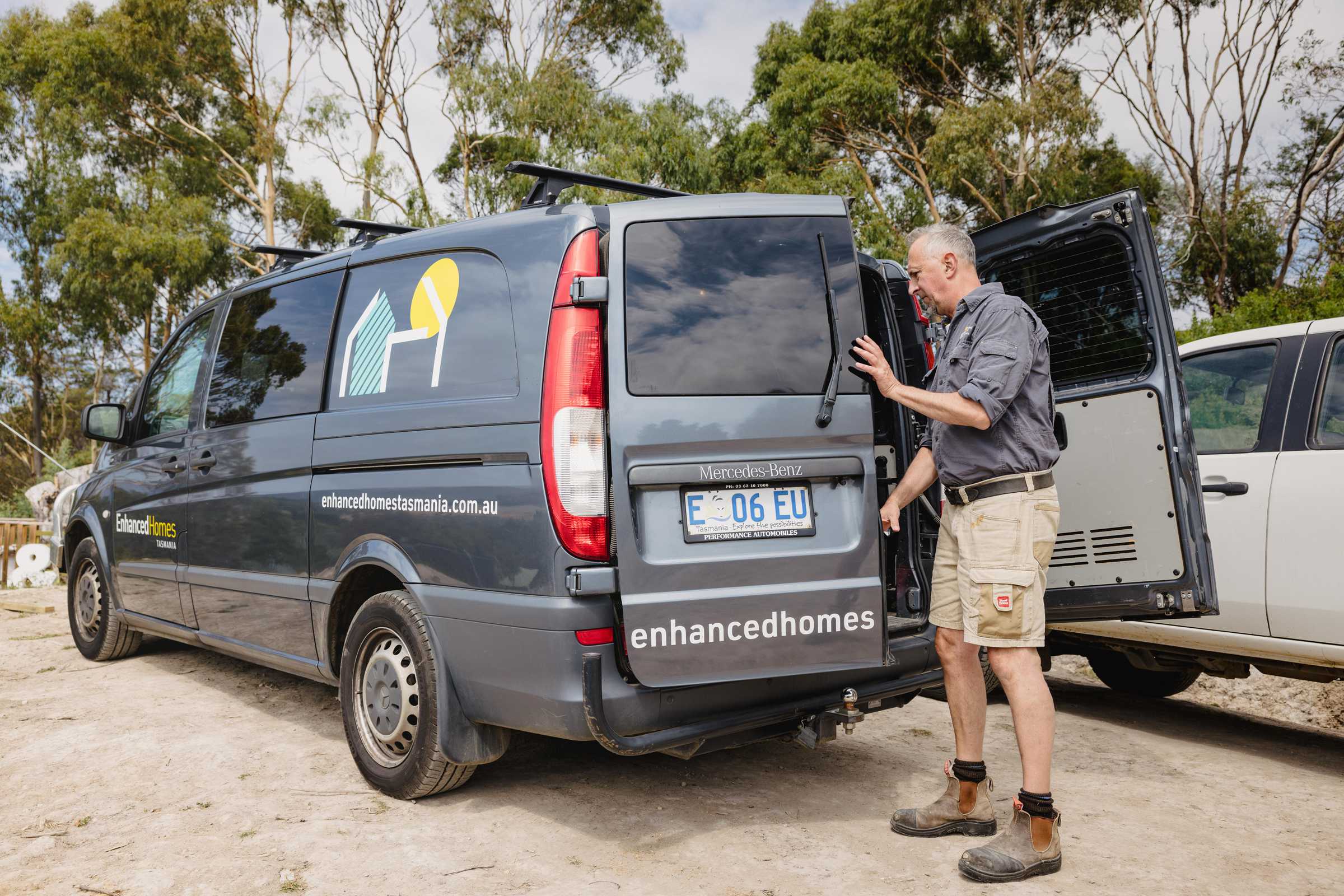 Experienced builder getting equipment from an Enhanced Homes Tasmania branded van. Photo: Jordan Davis.