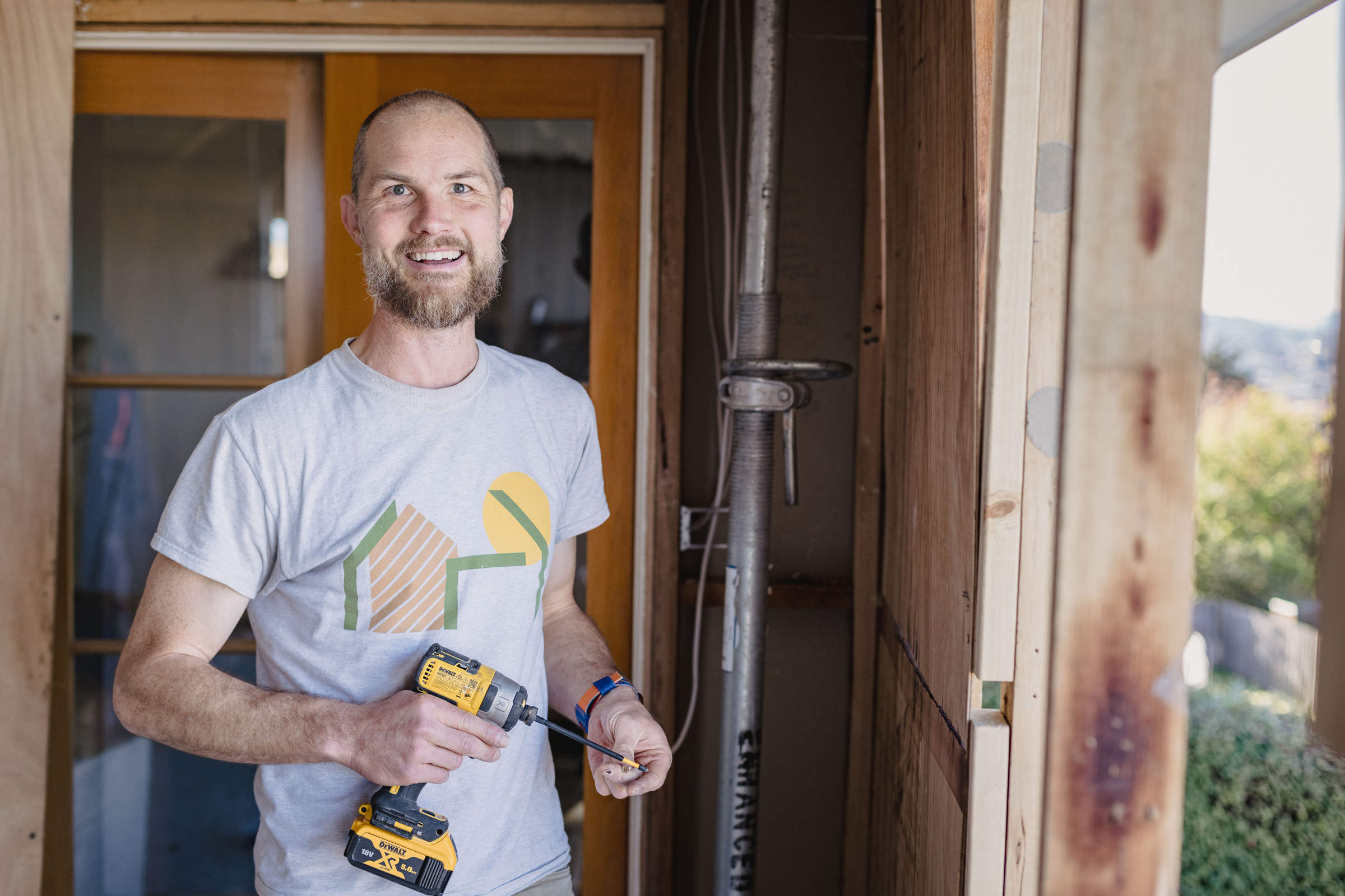 An adult apprentice, holding a drill and working on a home renovation, demonstrating teamwork and a positive team culture. Photo: Jordan Davis.