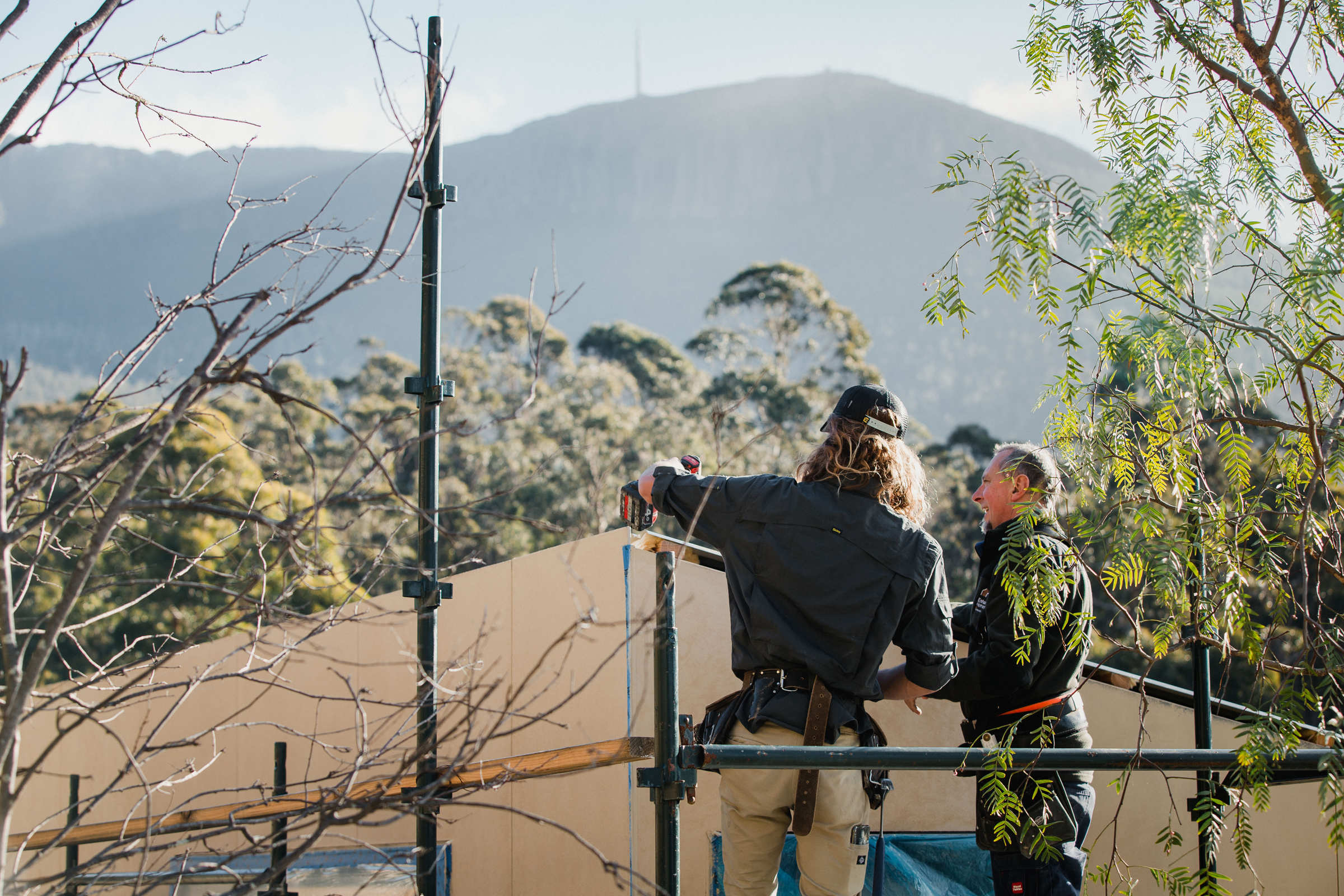 Experienced builder supporting and guiding the next generation of apprentices, with Hobart’s kunanyi / Mount Wellington in the background. Photo: Jordan Davis.