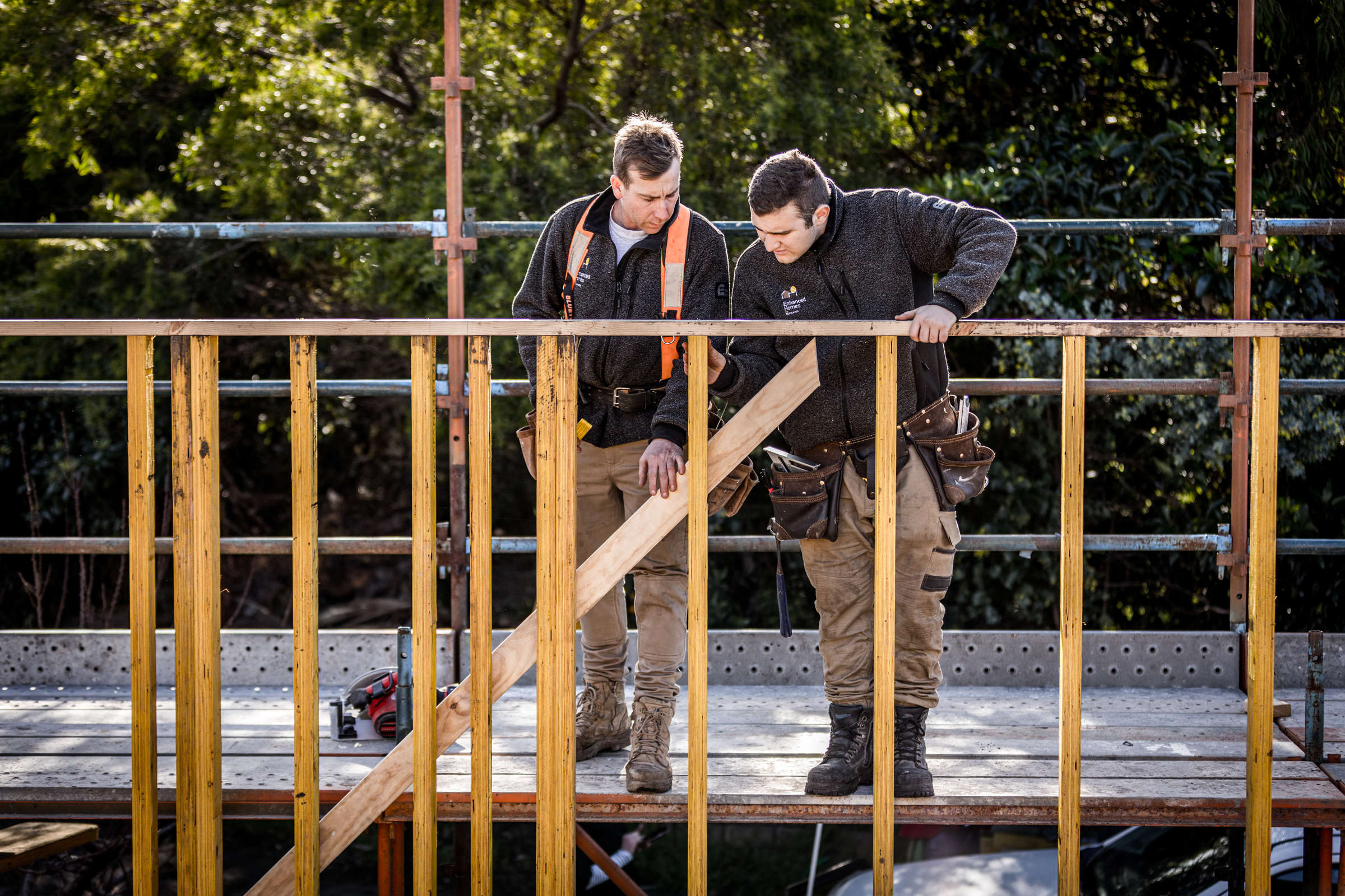 Experienced builder supporting and guiding the next generation of apprentices, teaching how to accurately read a plan and construct scaffolding in a safe manner as part of home renovation and extensions. Photo: Natalie Mendham.